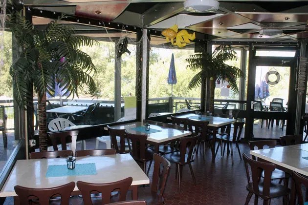 Überdachte Terrasse des Insel Cafés mit Palmen-Deko